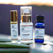 Load image into Gallery viewer, Three bottles of lavender essential oil on a wooden surface with a blurred natural background