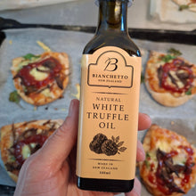 Load image into Gallery viewer, A hand holds a bottle of Bianchetto New Zealand Natural White Truffle Oil in front of a baking tray with pizza toppings.
